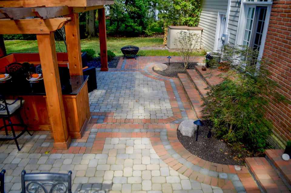 Paver patio and walk beside a brick house and timber posts